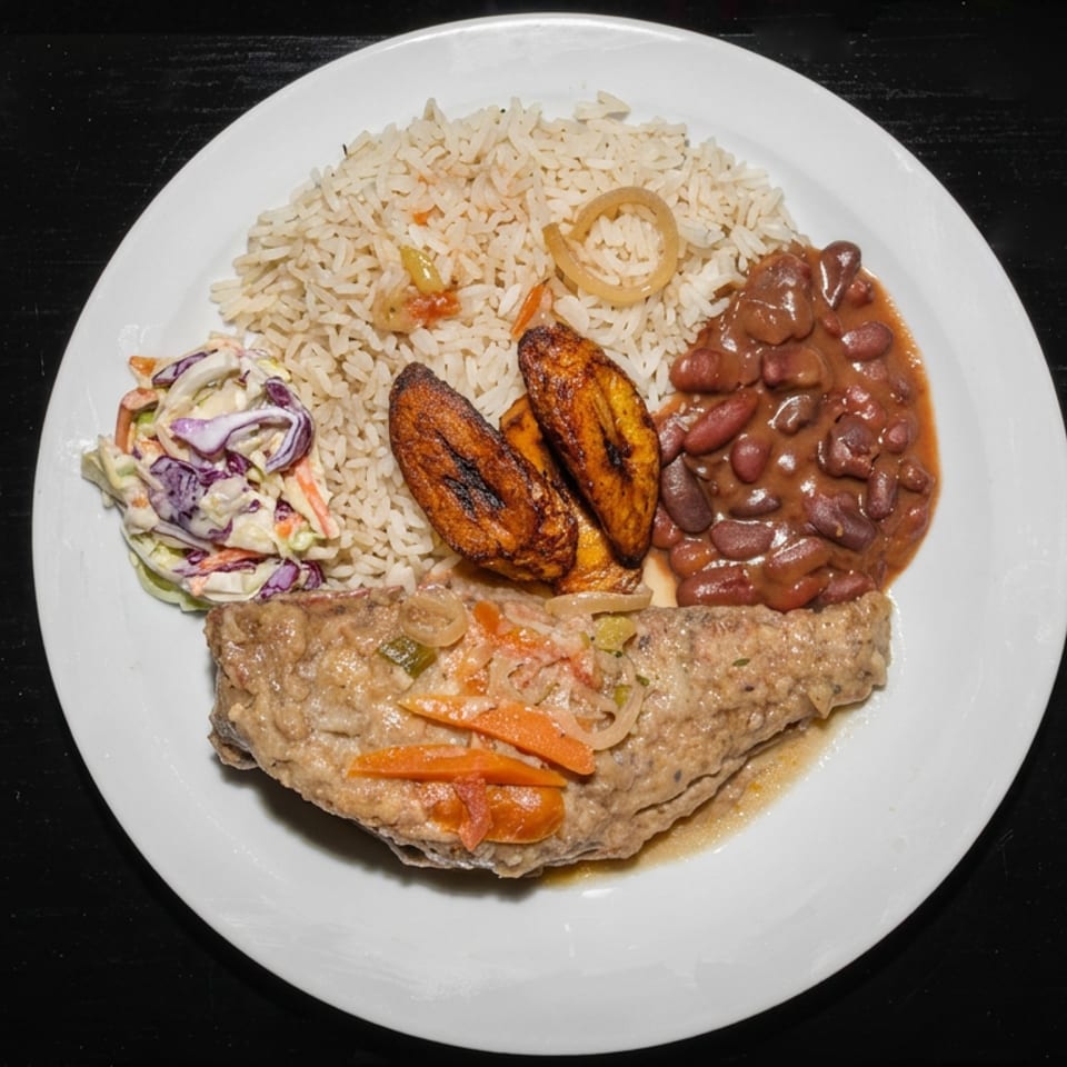 Plate of seasoned rice, beans, fried plantains, creamy slaw, and sauced meat topped with sautéed vegetables.
